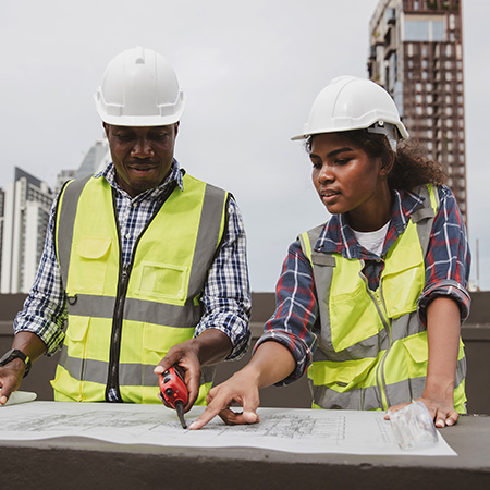two construction workers reviewing blueprints on rooftop site 7 construction strategies teamwork
