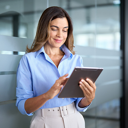woman using tablet in modern office space with a professional and relaxed expression showcasing digital productivity and technology skills