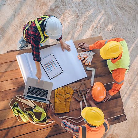 four construction workers discussing project plans with tools and documents on a wooden table essential strategies for 10 key projects