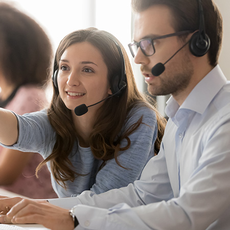 two customer service representatives engaged in a discussion wearing headsets focused on teamwork and collaboration for effective communication in a professional environment