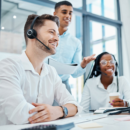 three smiling customer service representatives in a modern office environment with headsets working together